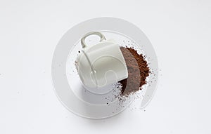 Ground roasted coffee sprinkled on white background and white coffee cup close up close up