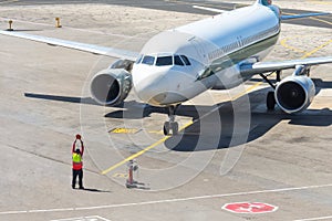 Ground staff airplane marshaller meets passenger plane after landing flight