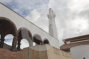 Ground view of colombian guatavita town clock tower with brick arc structure and blue cloudy sky