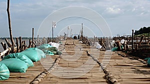 Ground view of an horse cart and motorbikes crossing the bamboo bridge