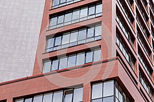 Ground view of modern building facade with red concrete walls, balcony windows