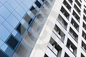 Ground view of tall modern building facade, blue and white smooth facade surface.