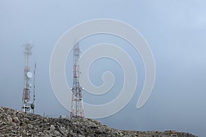 Ground view of telecommunication towers in the clouds on a mountain peak
