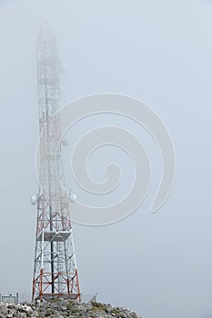 Ground view of telecommunication towers in the clouds on a mountain peak