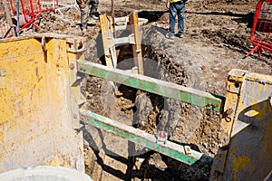 Ground workers installing trench support safety shoring system during deep drainage works on residential housing development