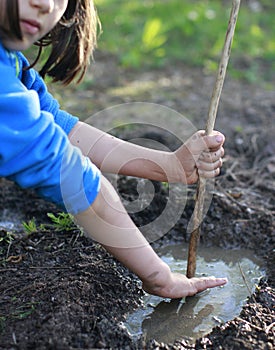 Grounded child playing with mud and stick for nature discovery