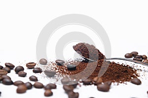 Grounded coffee in a spoon surrounded with beans isolated