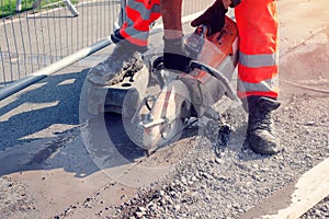 Groundworker cutting road with petrol saw