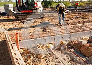 Groundworker is installing internal drainage for a house.