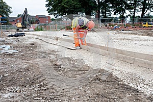 Groundworker making shutter for concrete to form base for kerb using scaffold boards and steel road pins during new road