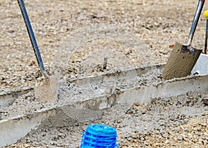 Groundworker placing wet concrete into formwork on building site