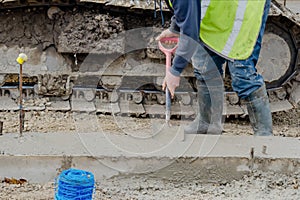 Groundworker placing wet concrete inside formwork during roadworks