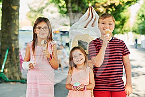 Group of 3 funny kids eating ice cream outdoors