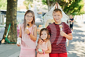 Group of 3 funny kids eating ice cream outdoors