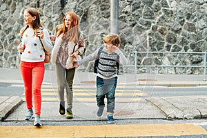 Group of 3 kids crossing the road, walking back to school