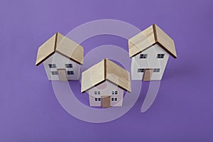 a group of 3 miniature houses lined up on a bright purple background