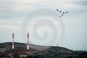 A group of 6 Russian fighter Fulcrum-A MiG 29 flies over the city industrial enterprise