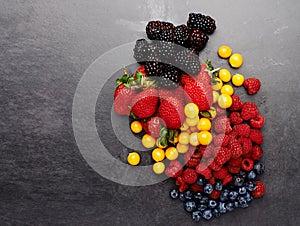 Group, above and fruit by dark background for fresh, smoothie and vegan diet on table with strawberry. Blueberry