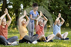 Group of active senior people attending outdoor yoga class with instructor