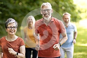 Group of active senior people running together outdoors in park