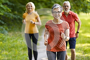 Group of active senior people running together outdoors in park