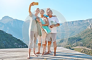 Group of active seniors posing together for a selfie or video call on a sunny day against a mountain view background