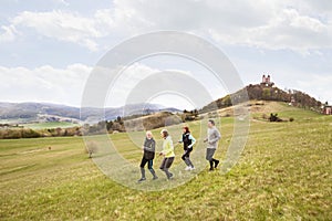 Group of seniors running outside on the green hills.