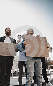 Group of activists giving slogans in a rally. Men and women marching together in a protest in the city.