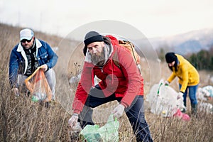 Group of activists picking up litter in nature, environmental pollution concept.