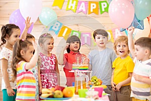 Group of adorable kids gathered around festive table. Birthday party for preschoolers