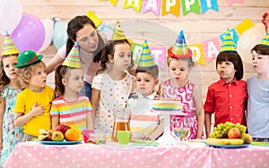 Group of adorable kids gathered around festive table. Birthday party for preschoolers