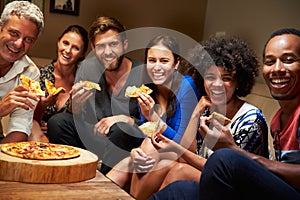 Group of adult friends eating pizza at a house party