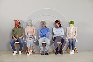 Group of adult people wearing funny animal masks waiting for job interview in office