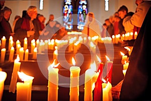 A group of adults and children light candles and pray in the church