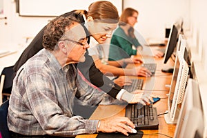 Group of adults learning computer skills. Intergenerational tran photo