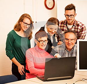 Group of adults learning computer skills. Intergenerational tran