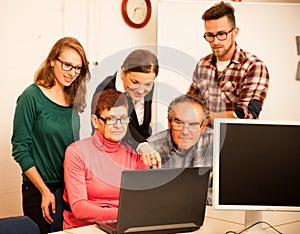 Group of adults learning computer skills. Intergenerational tran