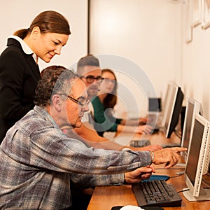 Group of adults learning computer skills. Intergenerational tran