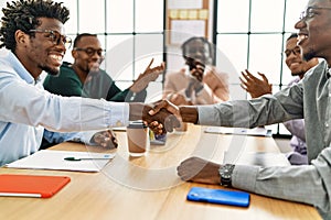 Group of african american business workers smiling and clapping to partners handshake at the office
