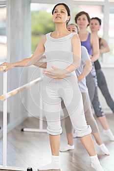 Group of amateurs of different ages practice ballet moves in classical dance class