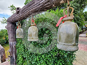 group of ancient lucky gold bell ring hanging on woonden pole. Thailand buddism tradition temple symbol