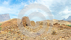 Group of ancient stone beehive tombs with Jebel Misht mountain in the background, archaeological site near al-Ayn, sultanate Oman photo