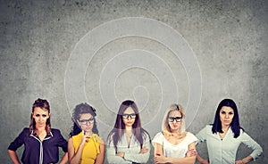 Group of angry negative young women looking at camera while standing against concrete wall background