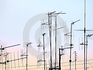 Group of antennas over an apartment with sunset background