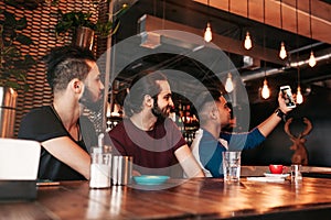 Group of arabian friends taking selfie in lounge bar. Mixed race young men having fun together