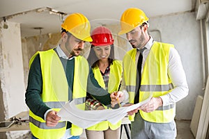 Group of architect watching some details on blueprints at construction site