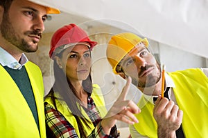 Group of architect watching some details on blueprints at construction site