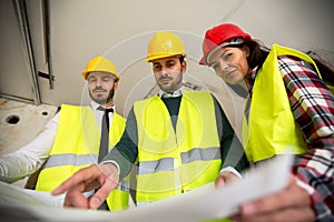 Group of architect watching some details on blueprints at construction site