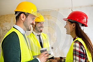 Group of architect watching some details on blueprints at construction site