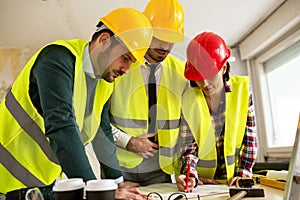 Group of architect watching some details on blueprints at construction site